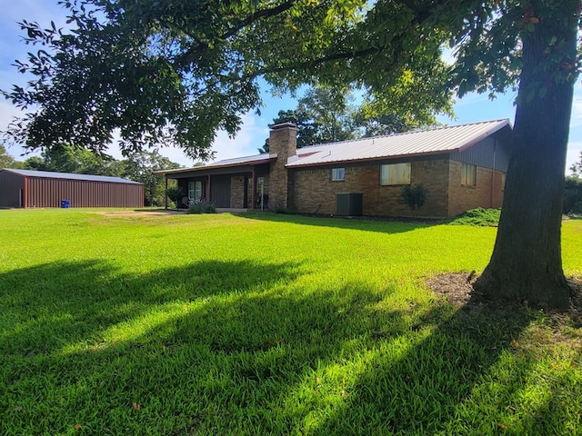 339 Liles Ln, Hudson, TX 75904 - rear view of property featuring a lawn, central air condition unit, a chimney, metal roof, and brick siding