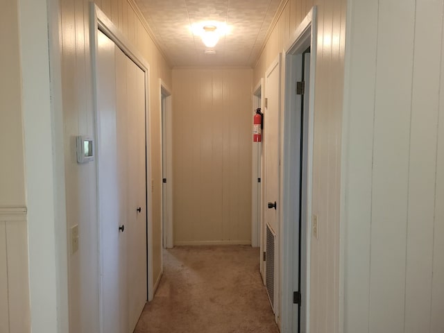 hallway featuring light colored carpet and crown molding