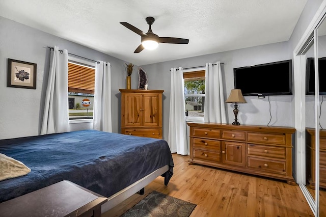 bedroom with a ceiling fan, light wood-style flooring, and a textured ceiling