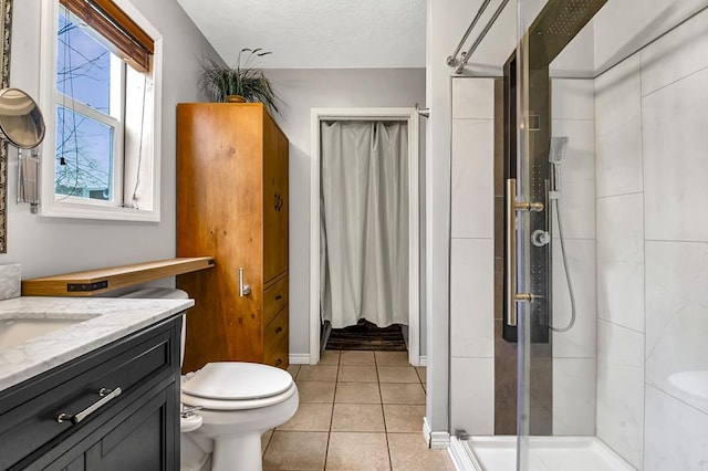 bathroom with a textured ceiling, tile patterned flooring, toilet, vanity, and a stall shower