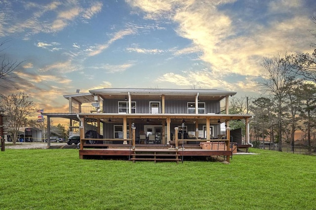 back of property at dusk featuring board and batten siding, a wooden deck, and a lawn