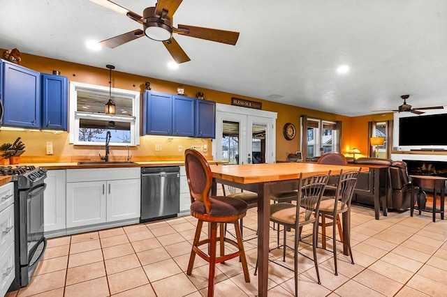 kitchen featuring blue cabinetry, light tile patterned floors, stainless steel dishwasher, gas stove, and a sink