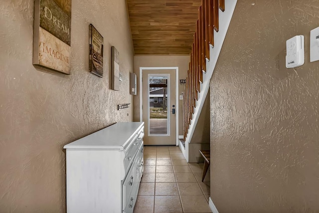 interior space featuring stairs, a textured wall, light tile patterned flooring, and wood ceiling