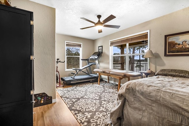 bedroom with a textured wall, a textured ceiling, baseboards, and wood finished floors