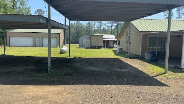 view of yard featuring cooling unit, a carport, a garage, and a storage unit