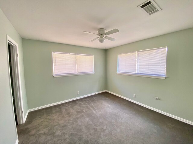 unfurnished room with ceiling fan and dark carpet