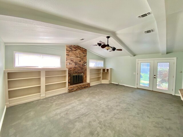 unfurnished living room featuring a healthy amount of sunlight, carpet floors, and vaulted ceiling