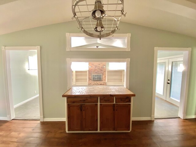 kitchen featuring vaulted ceiling, tile counters, french doors, and hardwood / wood-style flooring