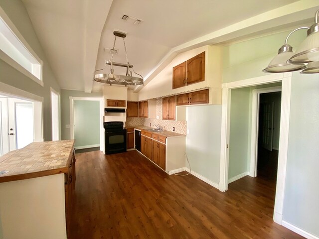 kitchen featuring lofted ceiling, black appliances, sink, hanging light fixtures, and dark hardwood / wood-style flooring