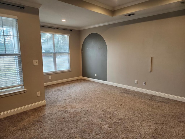 unfurnished room featuring visible vents, carpet floors, arched walkways, crown molding, and baseboards