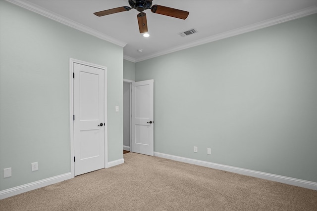 empty room with visible vents, light colored carpet, crown molding, and baseboards