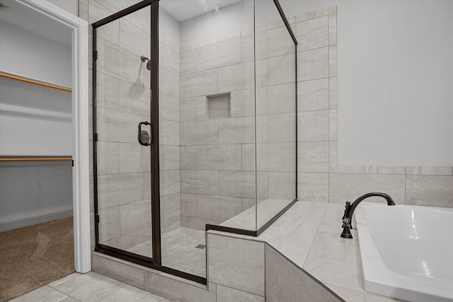 full bath featuring tile patterned floors, a stall shower, and a walk in closet