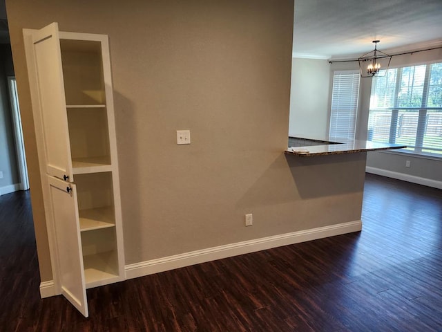 interior space with a chandelier, dark wood-type flooring, baseboards, and ornamental molding