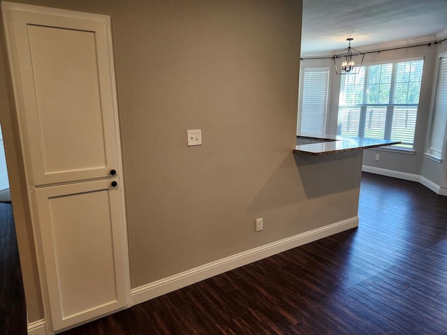 spare room featuring baseboards, a notable chandelier, and dark wood-style floors