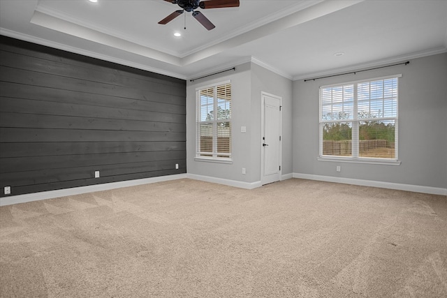 empty room featuring a tray ceiling, recessed lighting, carpet, crown molding, and baseboards