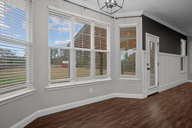 unfurnished dining area with a notable chandelier, crown molding, baseboards, and wood finished floors