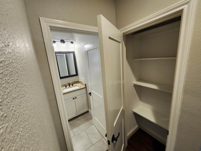 bathroom featuring tile patterned floors, vanity, and a textured wall