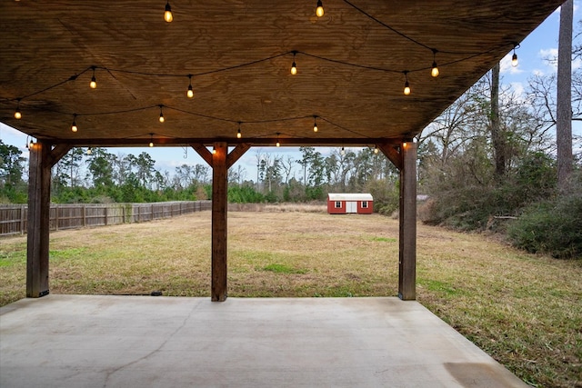 view of patio / terrace featuring an outbuilding, fence, and a shed