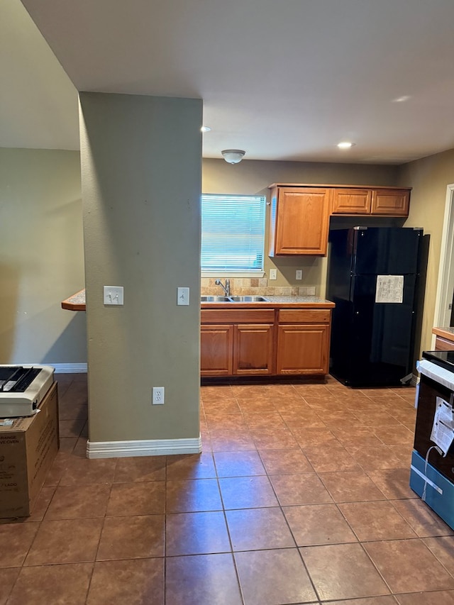 kitchen with light tile patterned flooring, electric range, black refrigerator, and sink