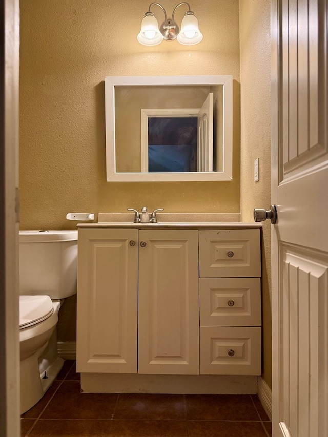 bathroom with toilet, vanity, and tile patterned floors