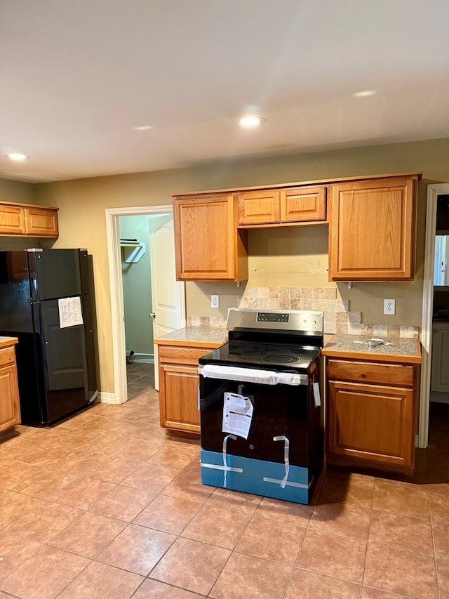 kitchen featuring black refrigerator, electric range, and light tile patterned floors