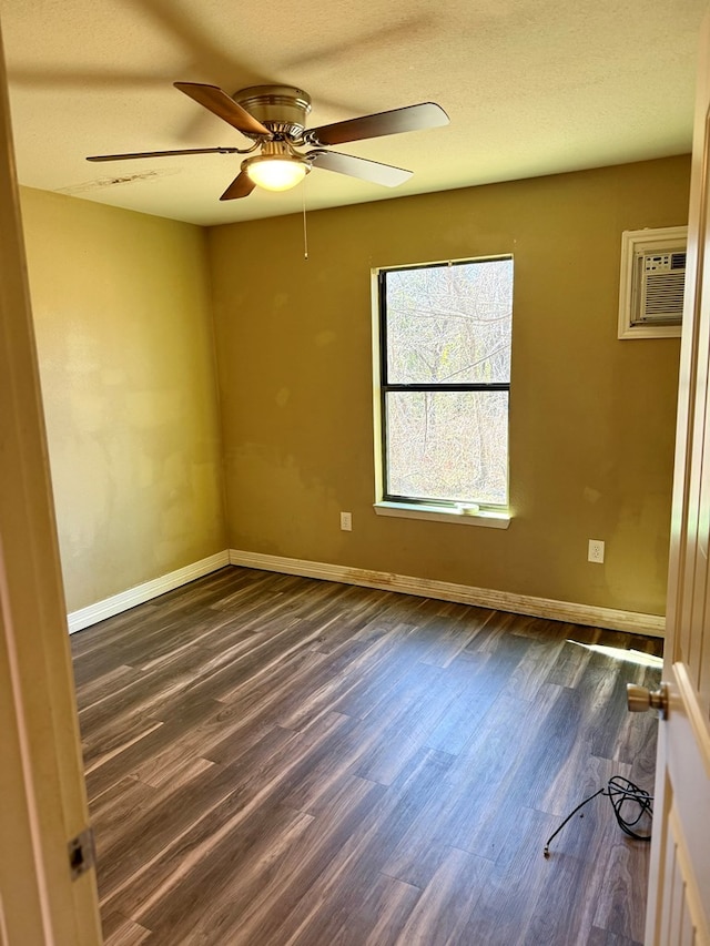 spare room featuring ceiling fan, an AC wall unit, and dark wood-type flooring