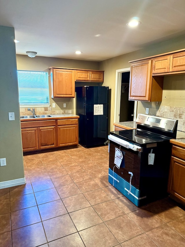 kitchen with black fridge, light tile patterned flooring, stainless steel electric stove, and sink