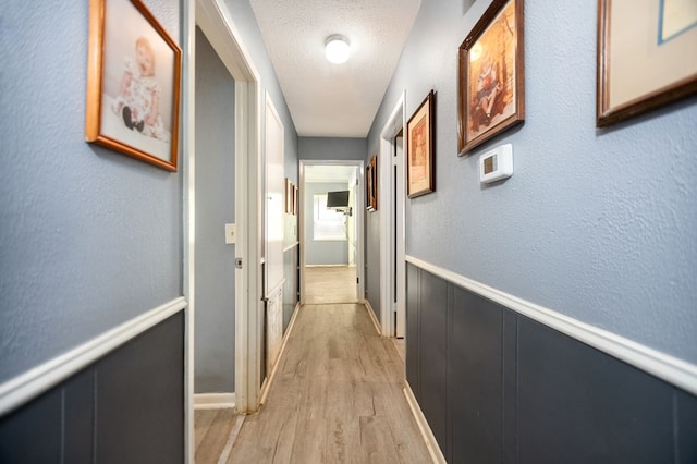 277 Mcclendon Rd, Lufkin, TX 75904 - corridor with light wood finished floors, a wainscoted wall, and a textured ceiling
