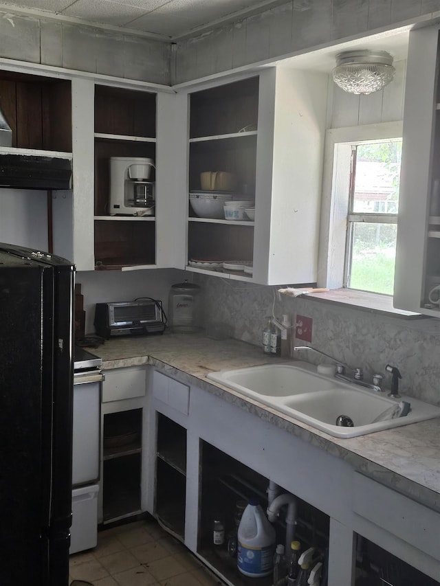 kitchen featuring tile patterned floors, black refrigerator, white stove, and sink