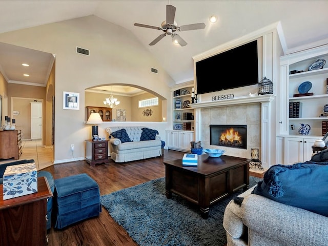 living room with a tile fireplace, built in shelves, lofted ceiling, and dark wood-type flooring