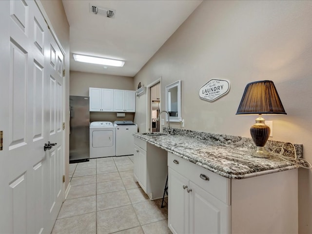 kitchen with white cabinets, light stone counters, sink, and washing machine and clothes dryer