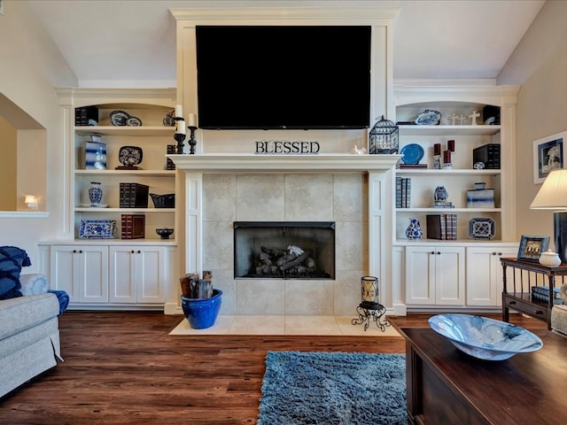 living room featuring dark hardwood / wood-style floors, a fireplace, and built in shelves