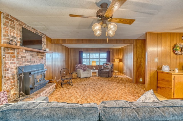 carpeted living room featuring ceiling fan, a wood stove, and wooden walls