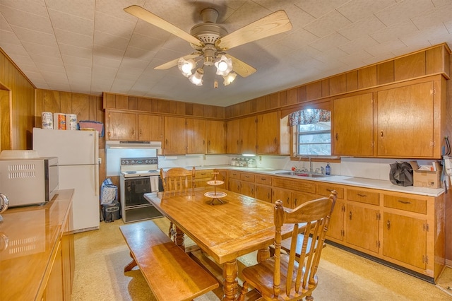 kitchen with range with electric cooktop, wooden walls, sink, white refrigerator, and ceiling fan