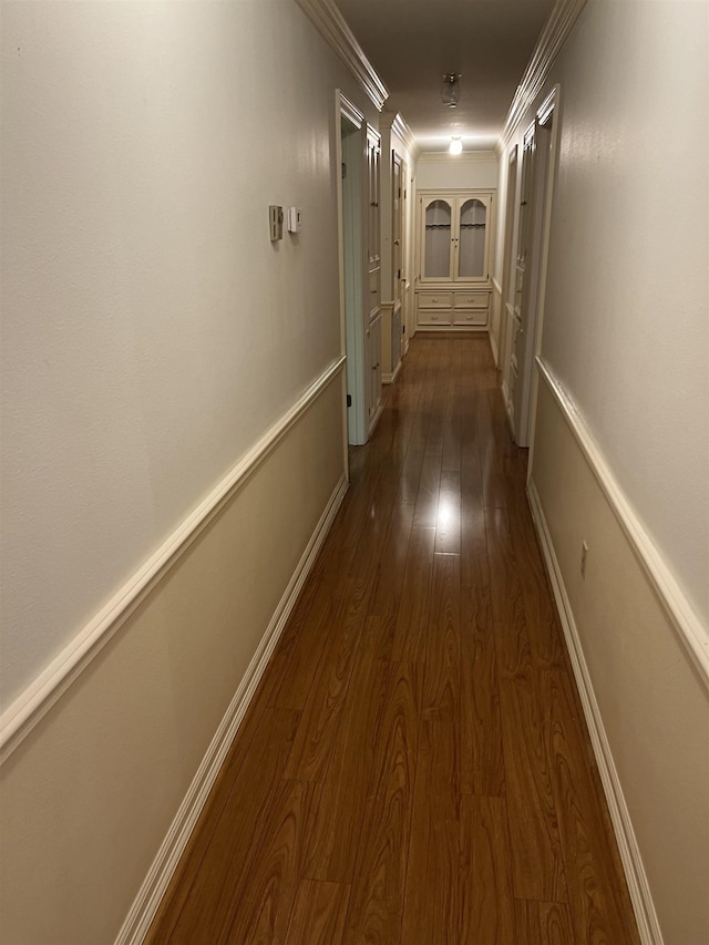 corridor with crown molding and dark wood-type flooring