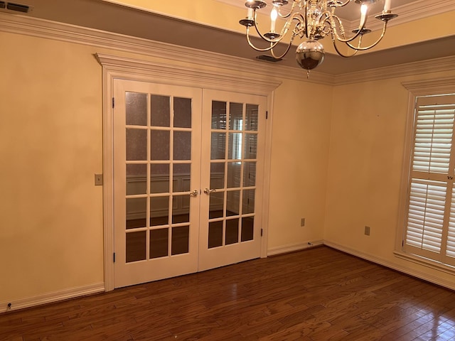 unfurnished room featuring ornamental molding, french doors, dark wood-type flooring, and an inviting chandelier