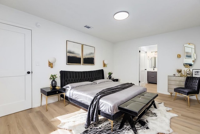 bedroom with light wood-type flooring and connected bathroom