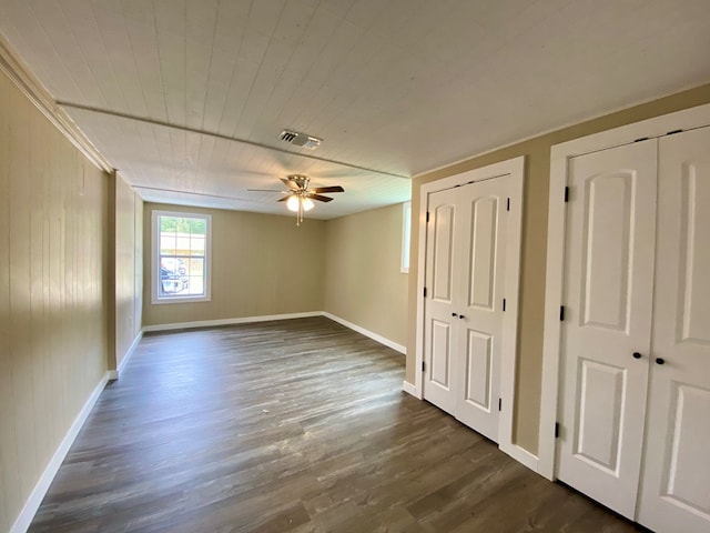 interior space featuring ceiling fan, dark wood-type flooring, and wood walls