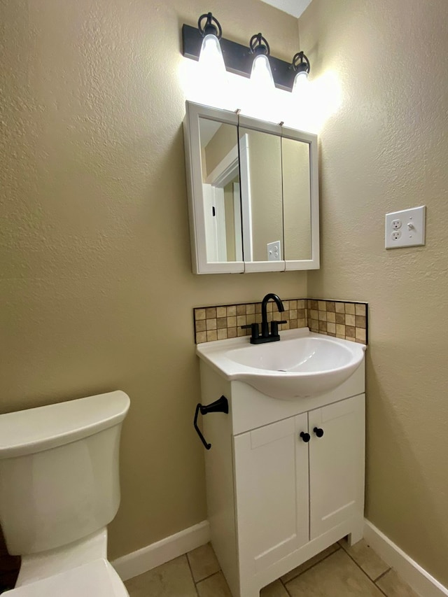 bathroom with toilet, vanity, and tile patterned floors