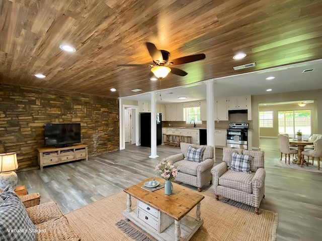 living room featuring a wealth of natural light, sink, wood ceiling, and light wood-type flooring