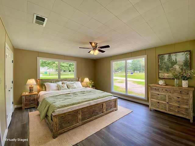 bedroom with ceiling fan, dark wood-type flooring, and multiple windows