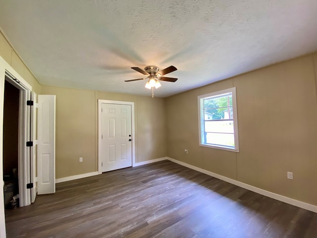 unfurnished room with ceiling fan, dark wood-type flooring, and a textured ceiling