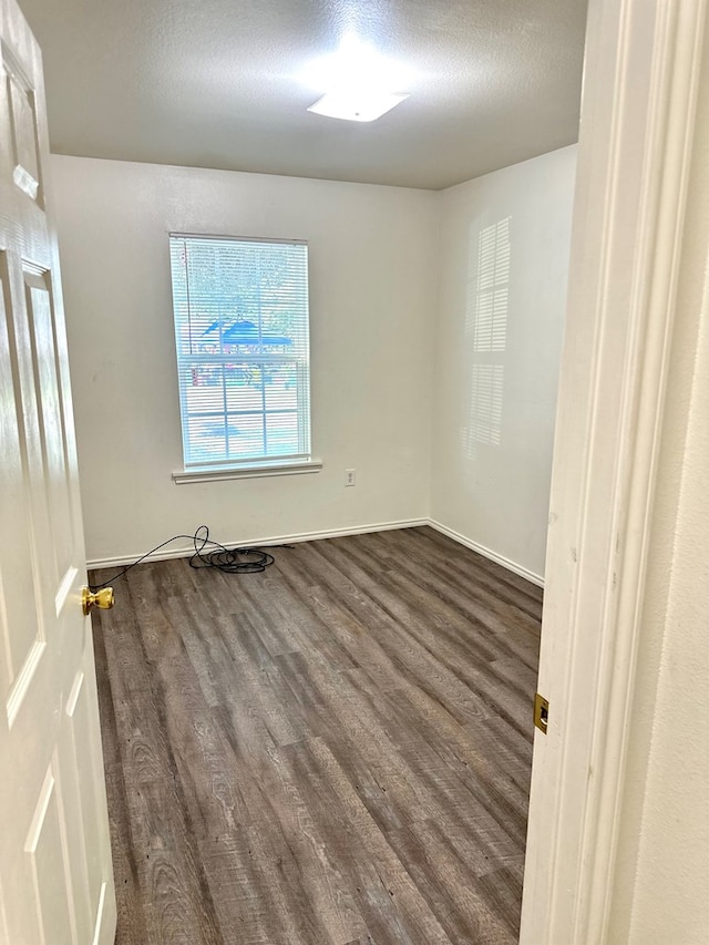 unfurnished room with a textured ceiling and dark wood-type flooring