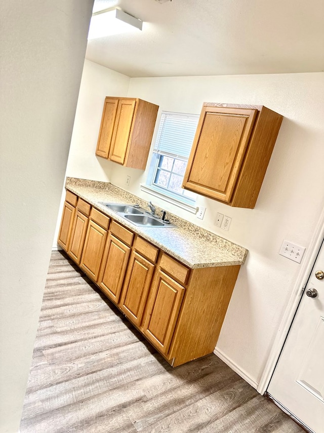 kitchen featuring light wood-type flooring, lofted ceiling, and sink