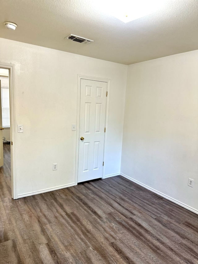 empty room featuring a textured ceiling and dark hardwood / wood-style flooring