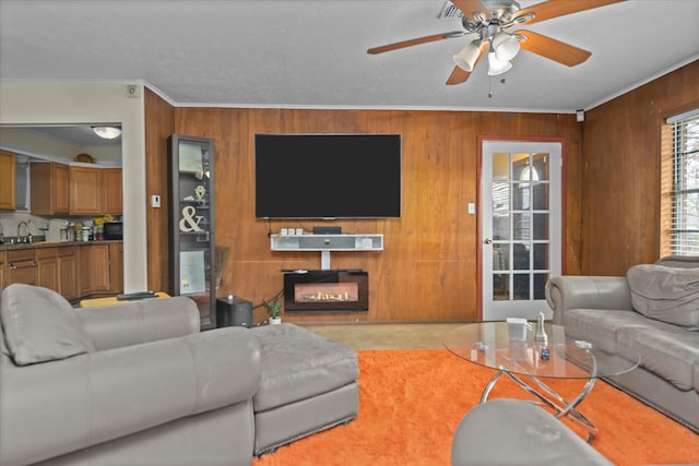 408 Bob St, Lufkin, TX 75904 - living area featuring wooden walls, crown molding, a ceiling fan, and a glass covered fireplace