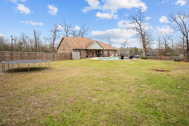 view of yard featuring a patio, a trampoline, a fenced backyard, and a fenced in pool