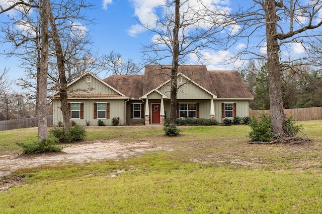 view of front of house with board and batten siding, roof with shingles, a front lawn, and fence