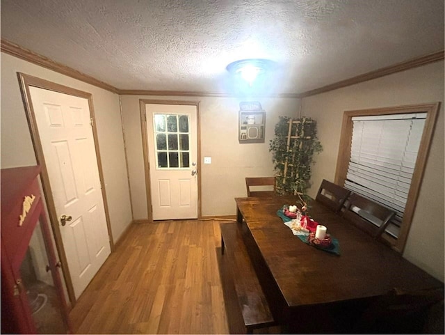 unfurnished dining area with light wood-type flooring, a textured ceiling, and crown molding