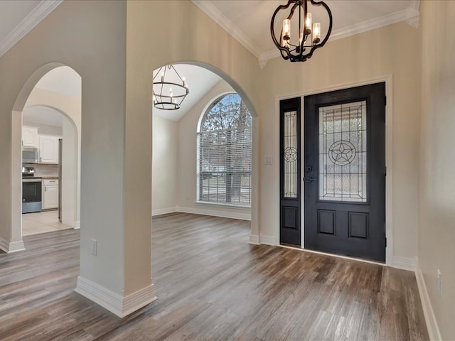 foyer entrance with ornamental molding, a chandelier, and light wood-type flooring